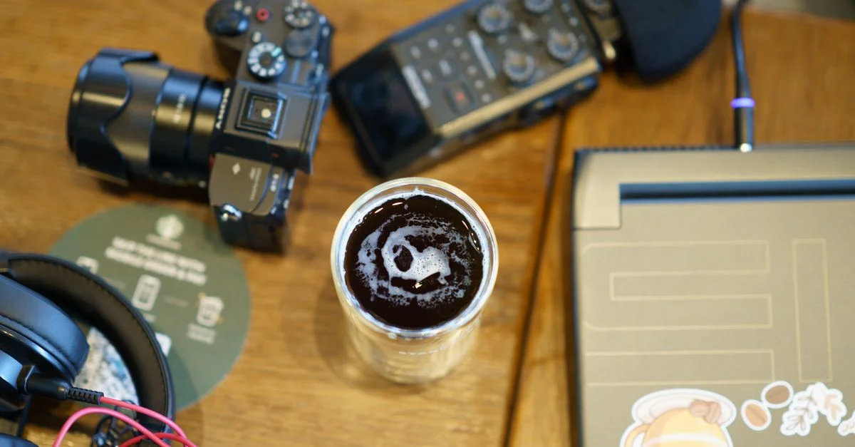 Vue aérienne d'un espace de travail comprenant une caméra, un casque audio, du matériel audio et une tasse de café.